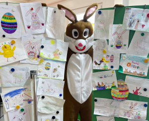 Osterhase steht zwischen zahlreichen selbstgemalten Bildern, die er von Kindern geschenkt bekommen hat