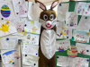 Osterhase steht zwischen zahlreichen selbstgemalten Bildern, die er von Kindern geschenkt bekommen hat